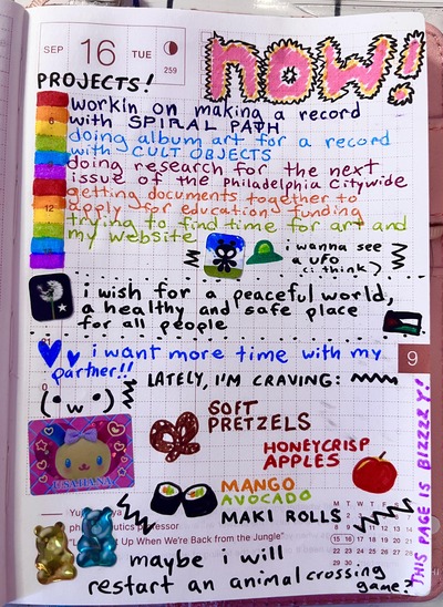 A page from my journal. It says 'Now' in colorful letters at the top. Under projects it says 'workin on making a record with spiral path, doing album art for a record with cult objects, doing resarch for the next issue of the philadelphia citywide, getting documents together to apply for education funding, trying to find time for my art and my website.' There's a sticker of an alien and a drawing of a spaceship that says 'I wanna see a UFO...I think', a sticker of a dandelion and a drawing of the Palestinian flag that says 'I wish for a peaceful world, a healthy and safe place for all people'. Next to some hearts it says 'I want more time with my partner!' and beneath that, a section with drawings of food I'm craving lately, such as soft pretzels, honeycrisp apples and mango avocado maki rolls. Finally, it says 'maybe i will restart an animal crossing game' beside a few gummy bear stickers.